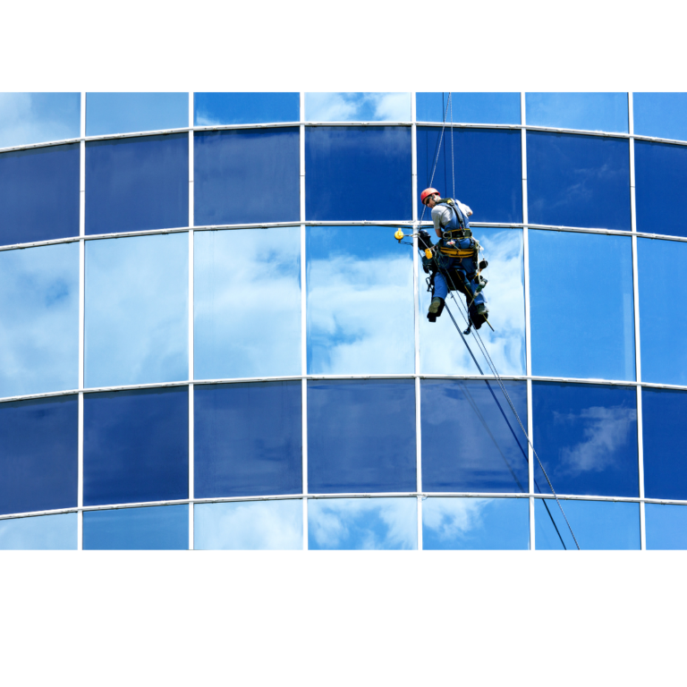 Worker seen with harness and ropes cleaning a high-rise window